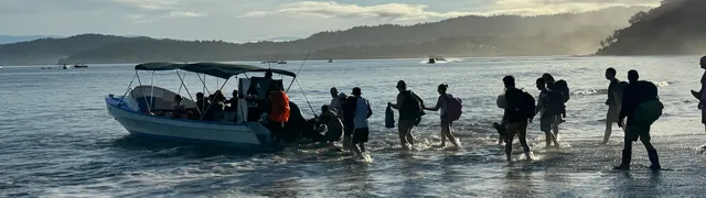 Travellers beside a boat on the beach
